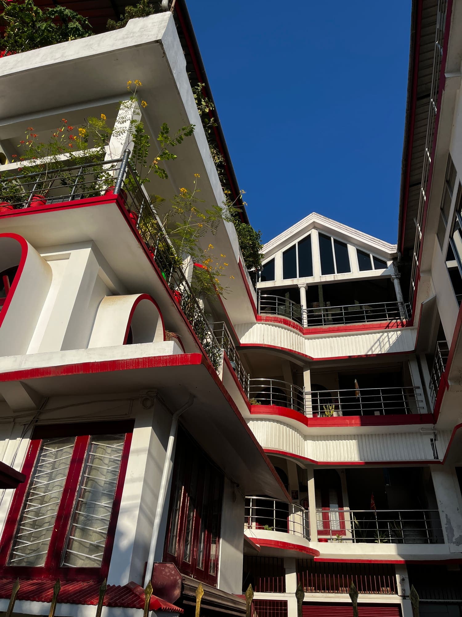 Front of the building with plant-filled balconies and the glass-gabled wing behind