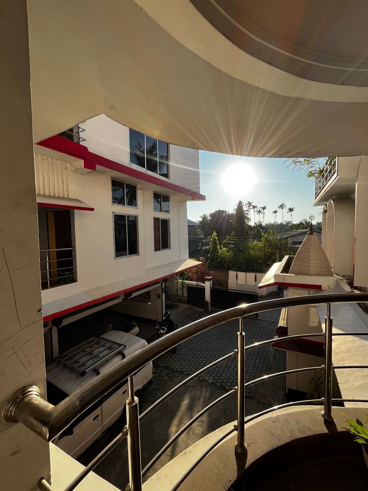 Curved steel balcony rail overlooking the courtyard in the afternoon sun